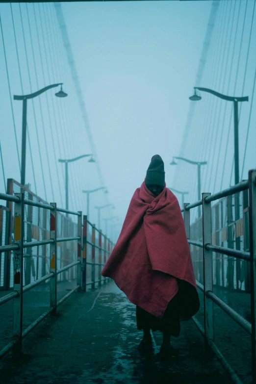 a person wearing a red cape crosses a bridge