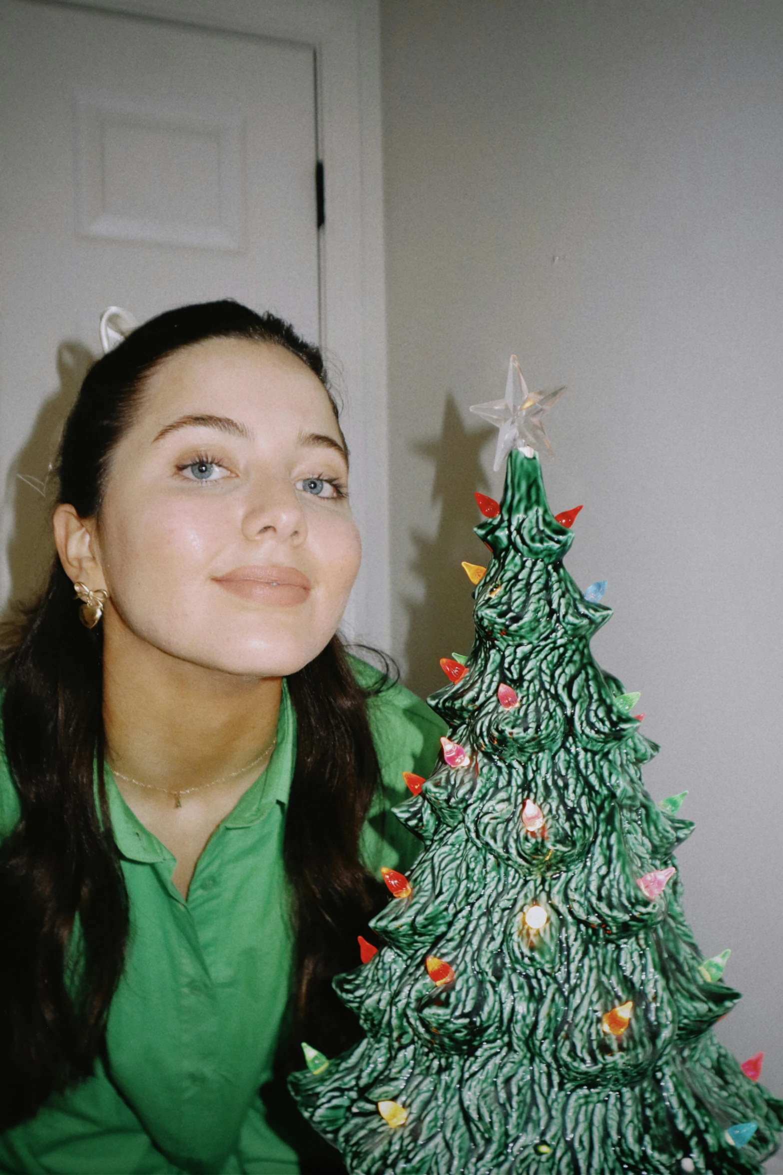 there is a woman that is smiling next to the christmas tree