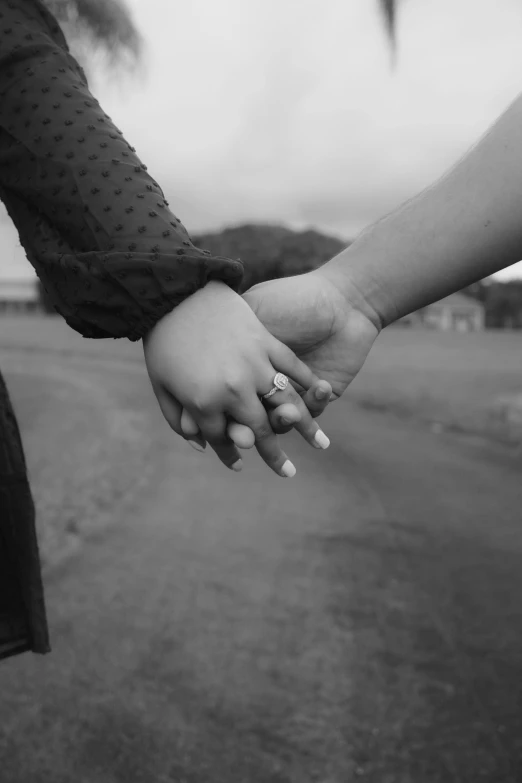 two people holding hands while walking down a road