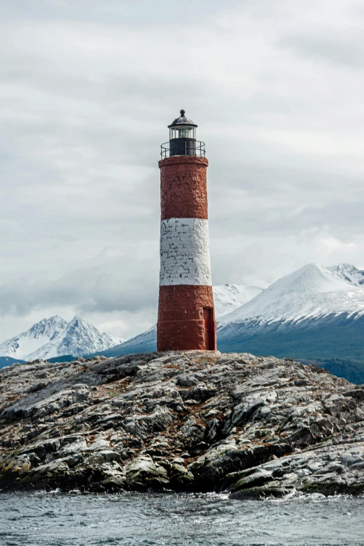 a lighthouse sits on the top of a rocky outcrop