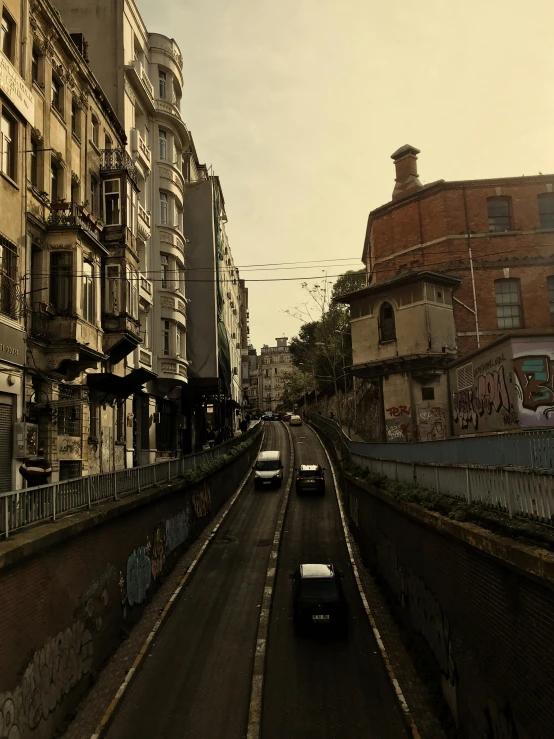 cars are driving down the street on a cloudy day