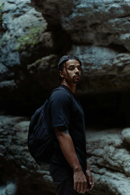 a man wearing a backpack walks through the woods