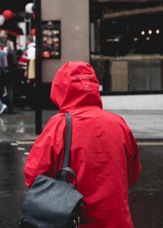 a person in a raincoat and a backpack walking across a street