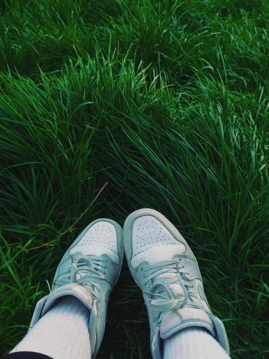 a person is standing in grass with tennis shoes on