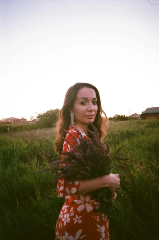 woman in floral dress in grassy area with airplane flying in background