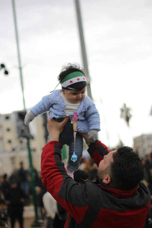 a man holding a little girl up in the air