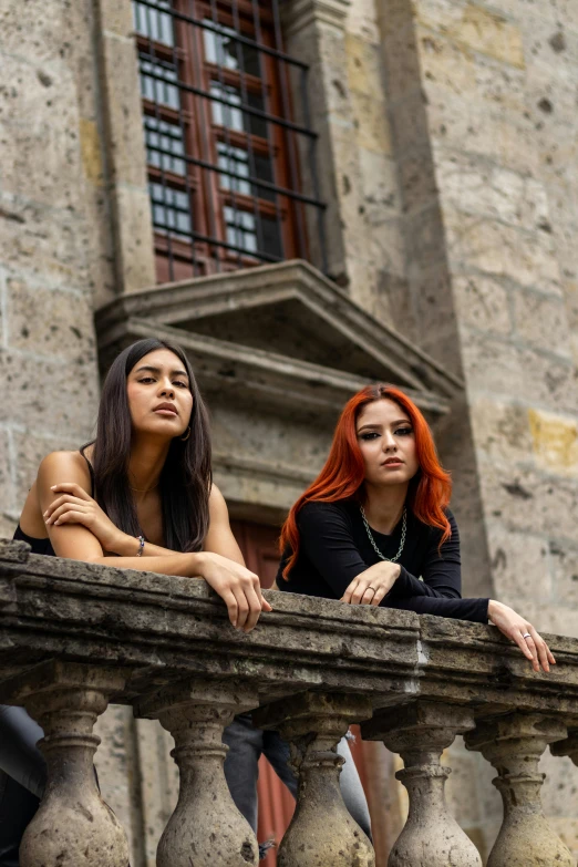 two women standing on the ledge of a tall building