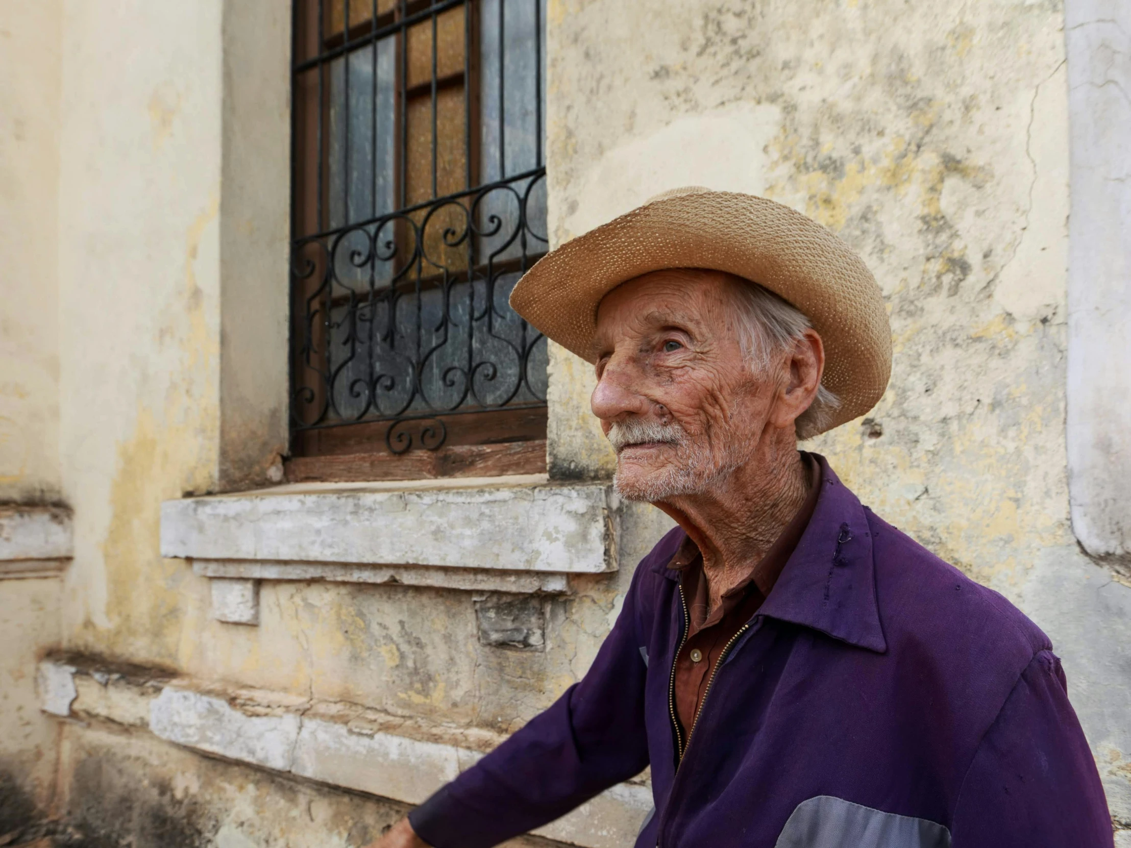 an elderly man in a hat walks past a building