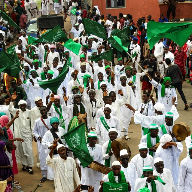 a group of people walking through a street with green flags