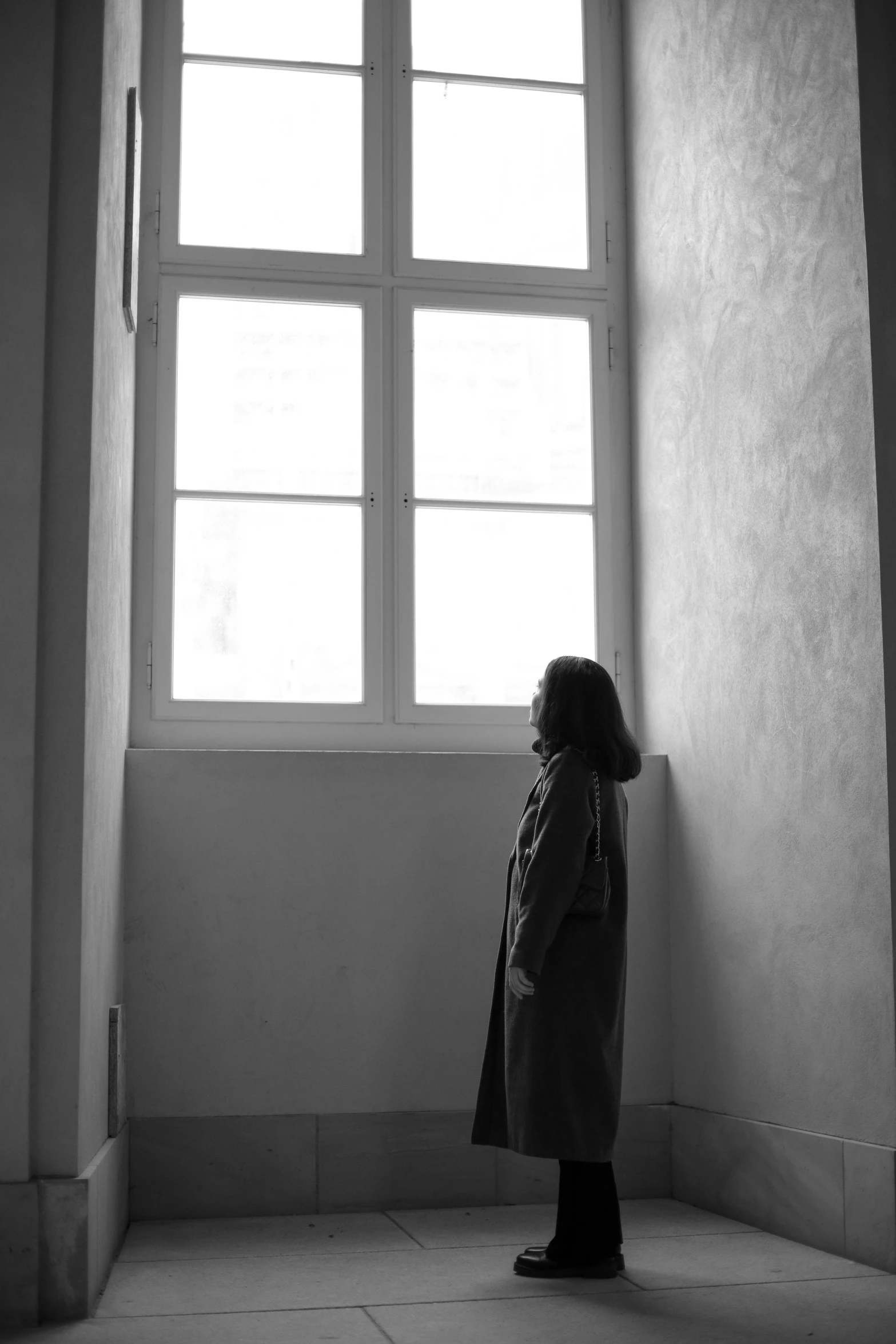 a woman stands in front of an open window