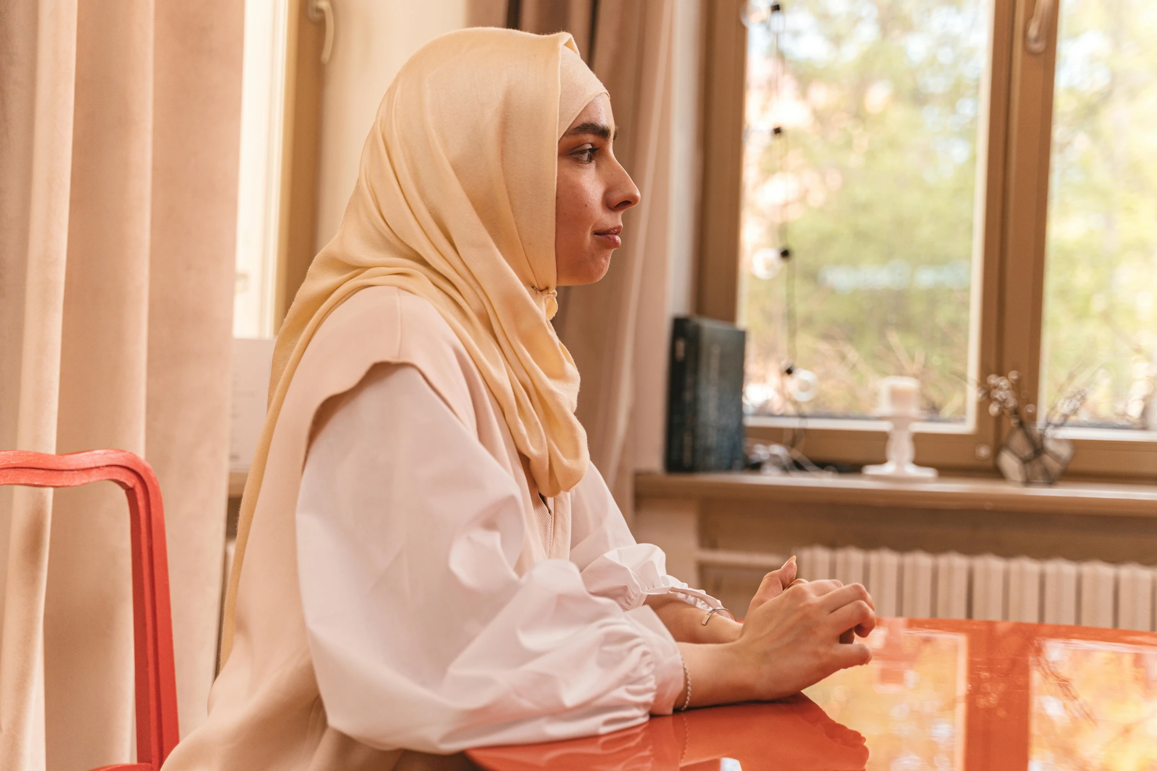 a woman sitting at a table praying her hands