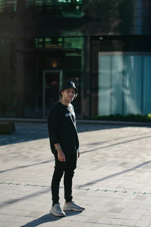 a man in a black cap is standing on the sidewalk