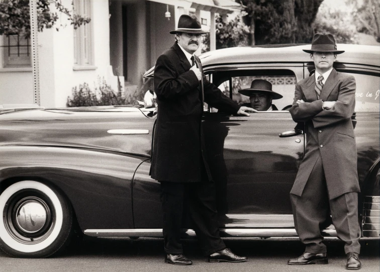 two men are standing next to a classic car