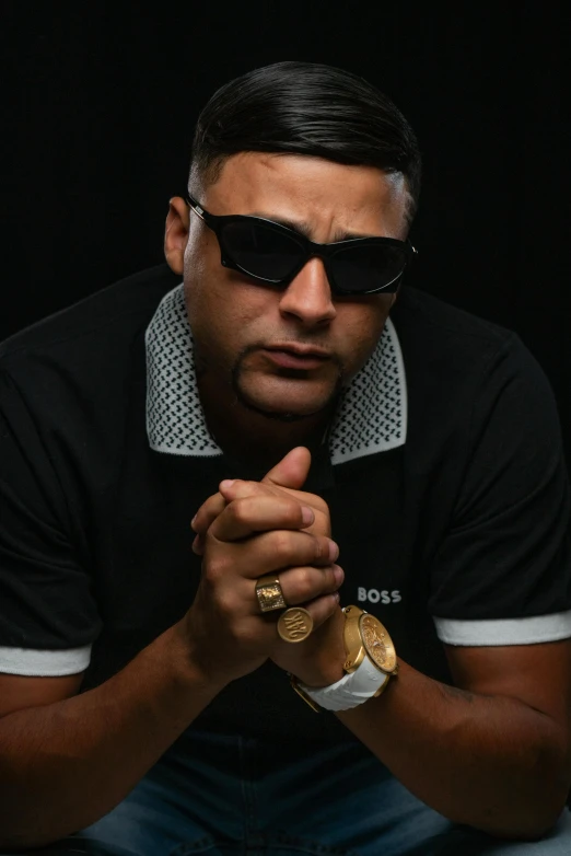 a man is sitting down in sunglasses, praying