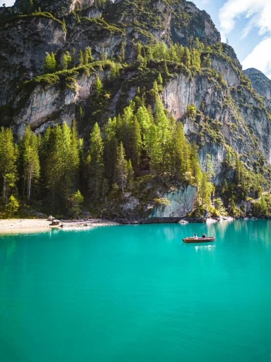 a boat in clear blue water near a cliff