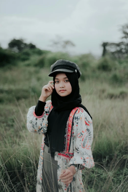 a woman wearing a scarf and hat in some grass