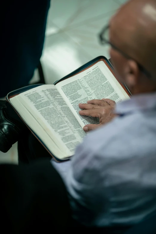 an old man is reading a bible in his lap