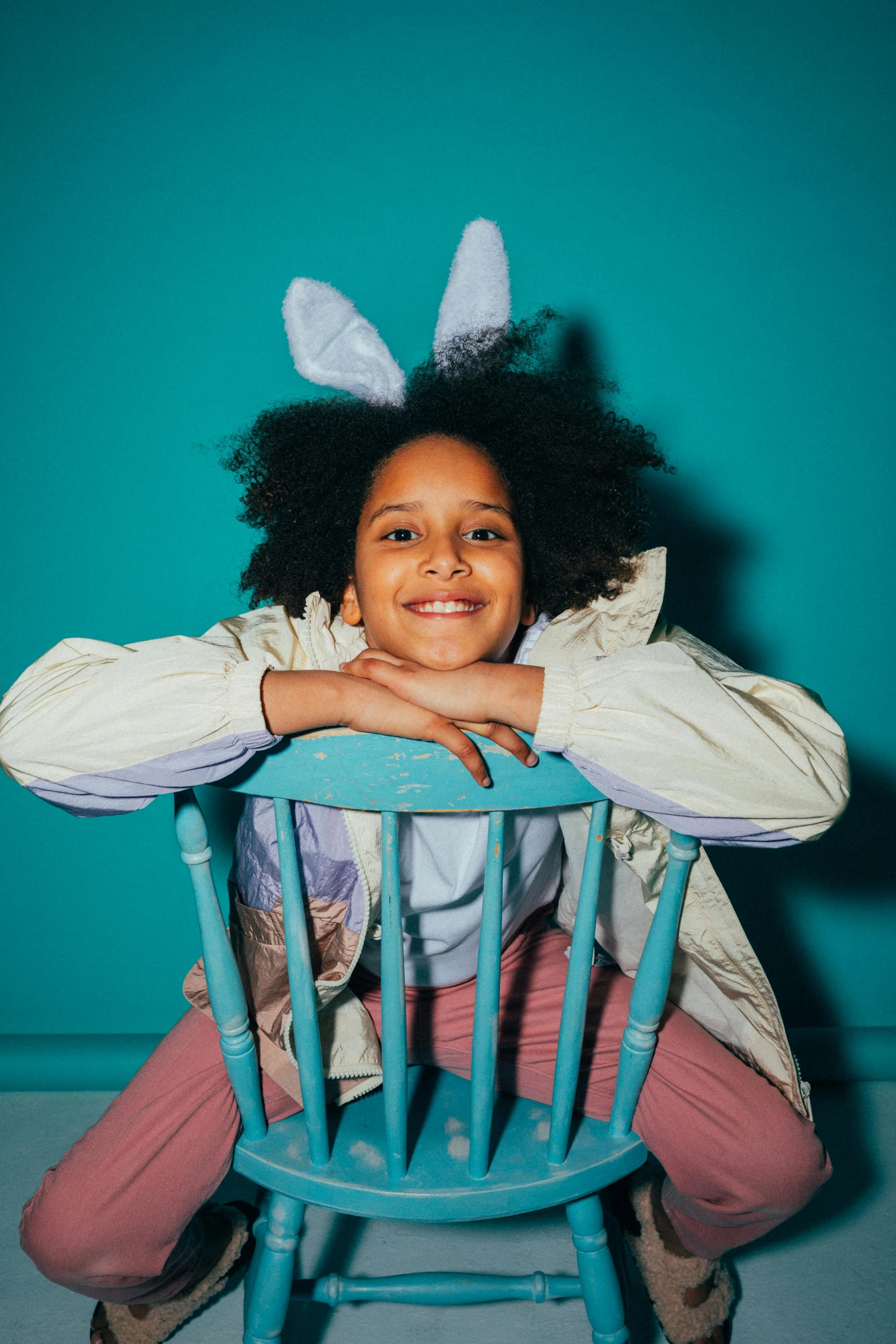 a little girl is sitting on a chair with two bunny ears