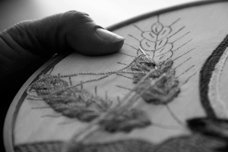 a woman's hand holding onto a large decorated embroidery project