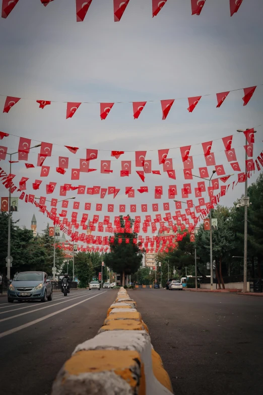 many square flags that have been flown from buildings over a street