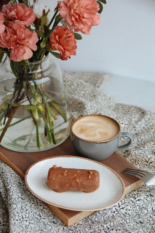 two cups of coffee are next to some pink flowers