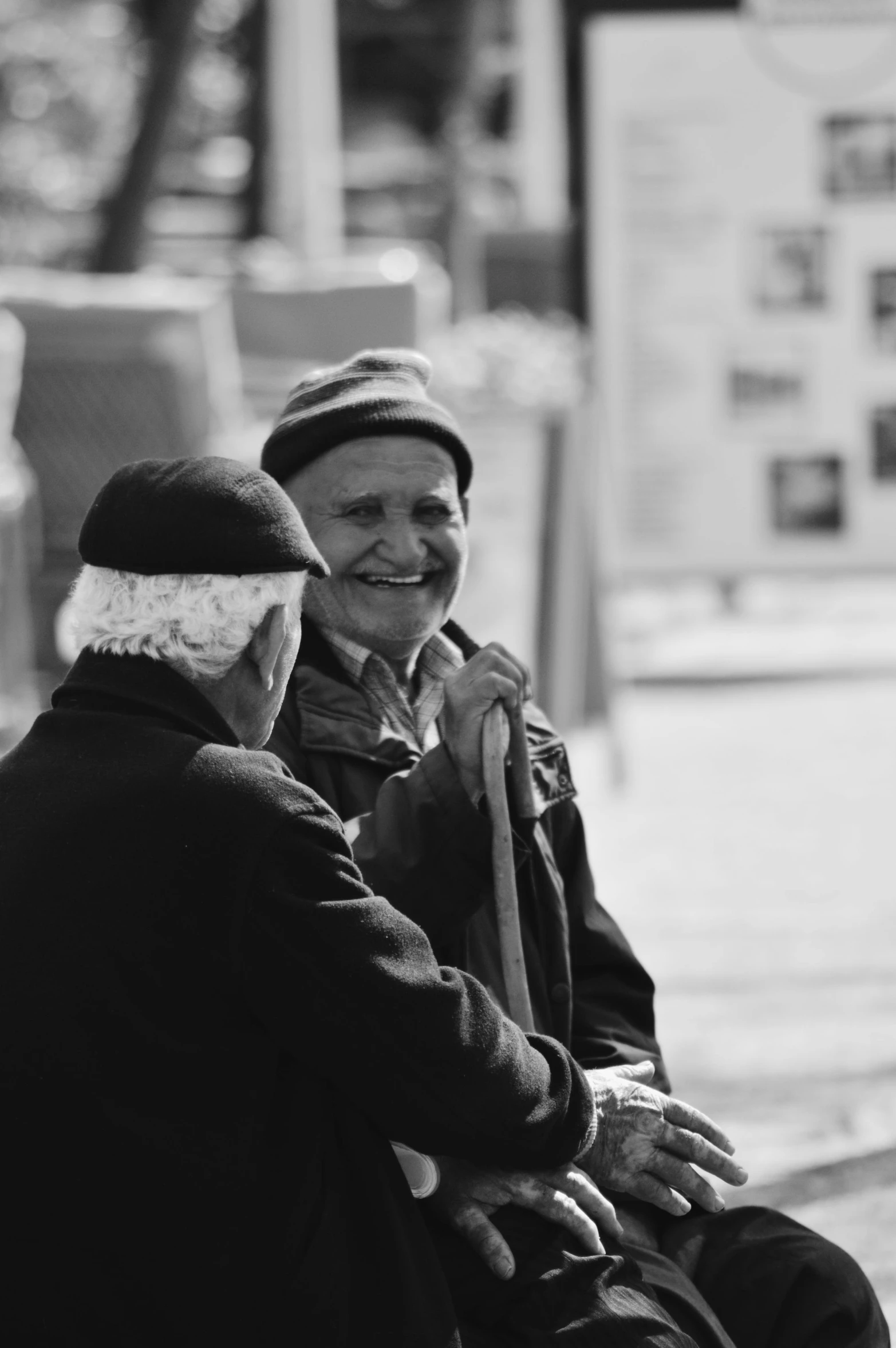 two people talking and smiling while sitting on the curb