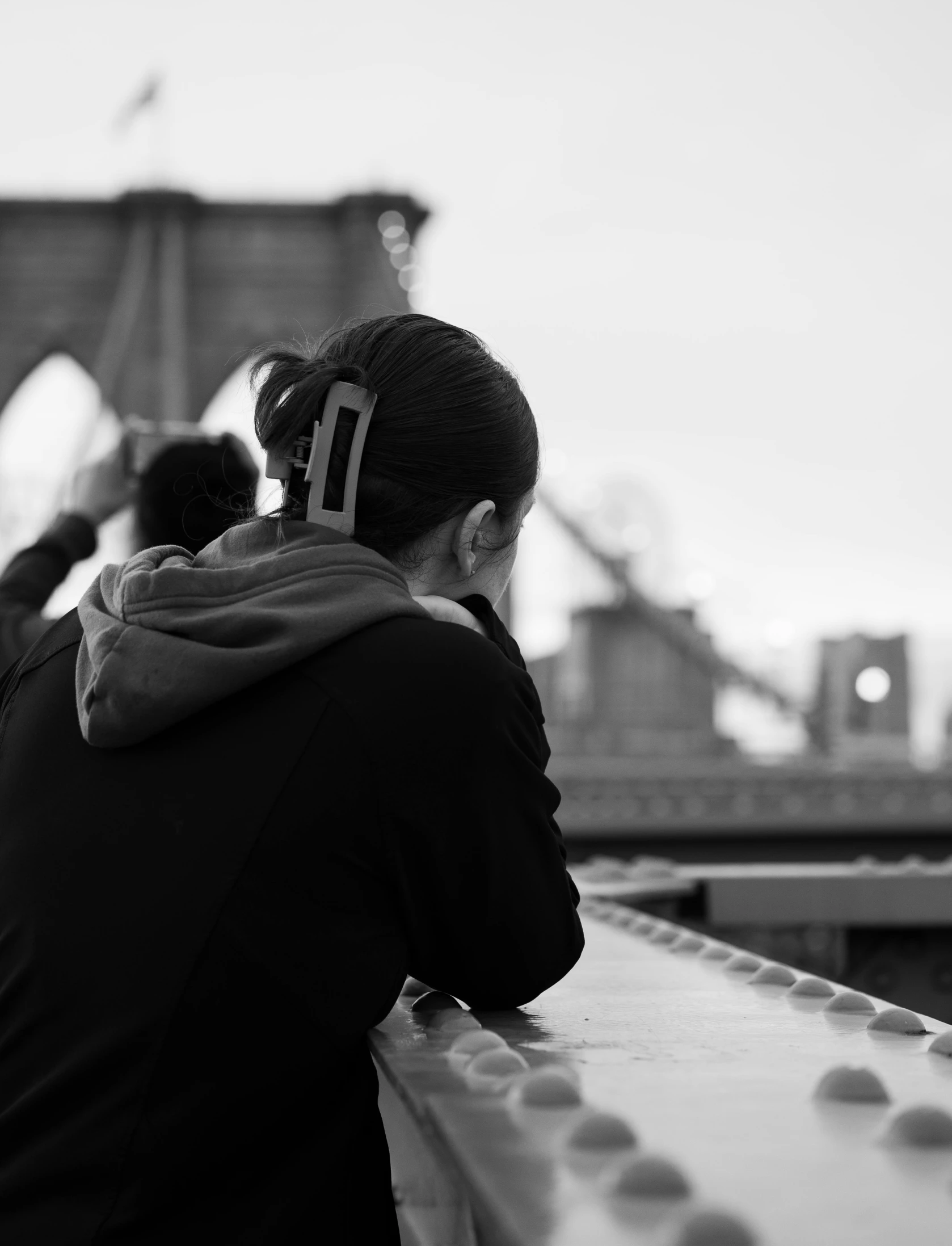 a person with a phone sits on the ledge near an overpass