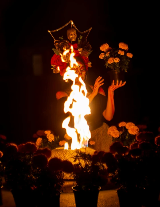 a person dressed as a devil with torches behind