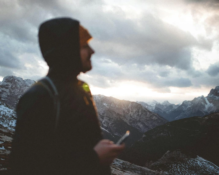 a man holding his cell phone in front of the mountain