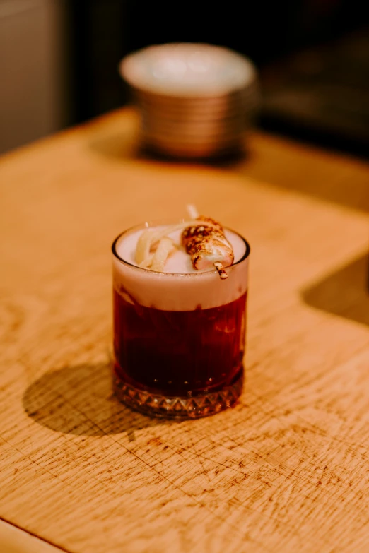 a glass on a table containing some liquid and ice