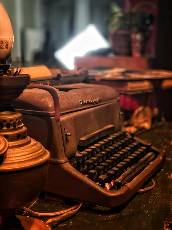 a typewriter, vase and other items sit on a table