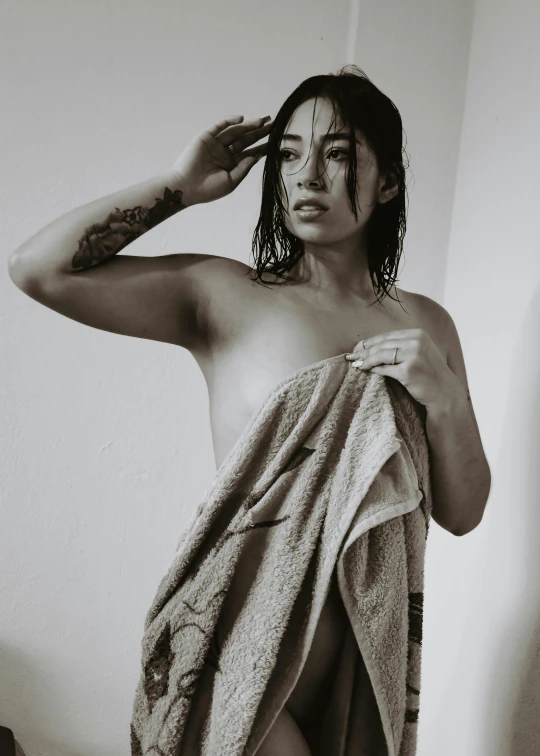 a  woman with tattoos on her head, holding a towel and standing