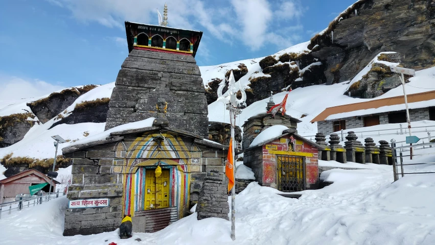 a small tower is made of stone and sits among snow