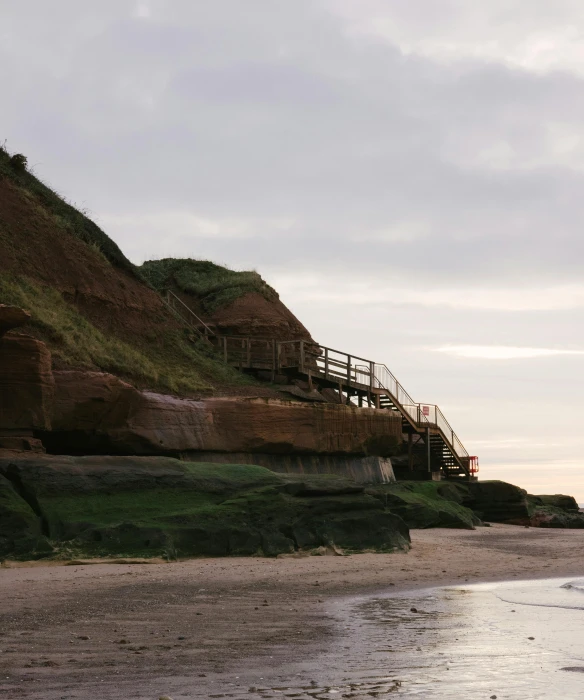 a beach next to a grassy hill with steps down it