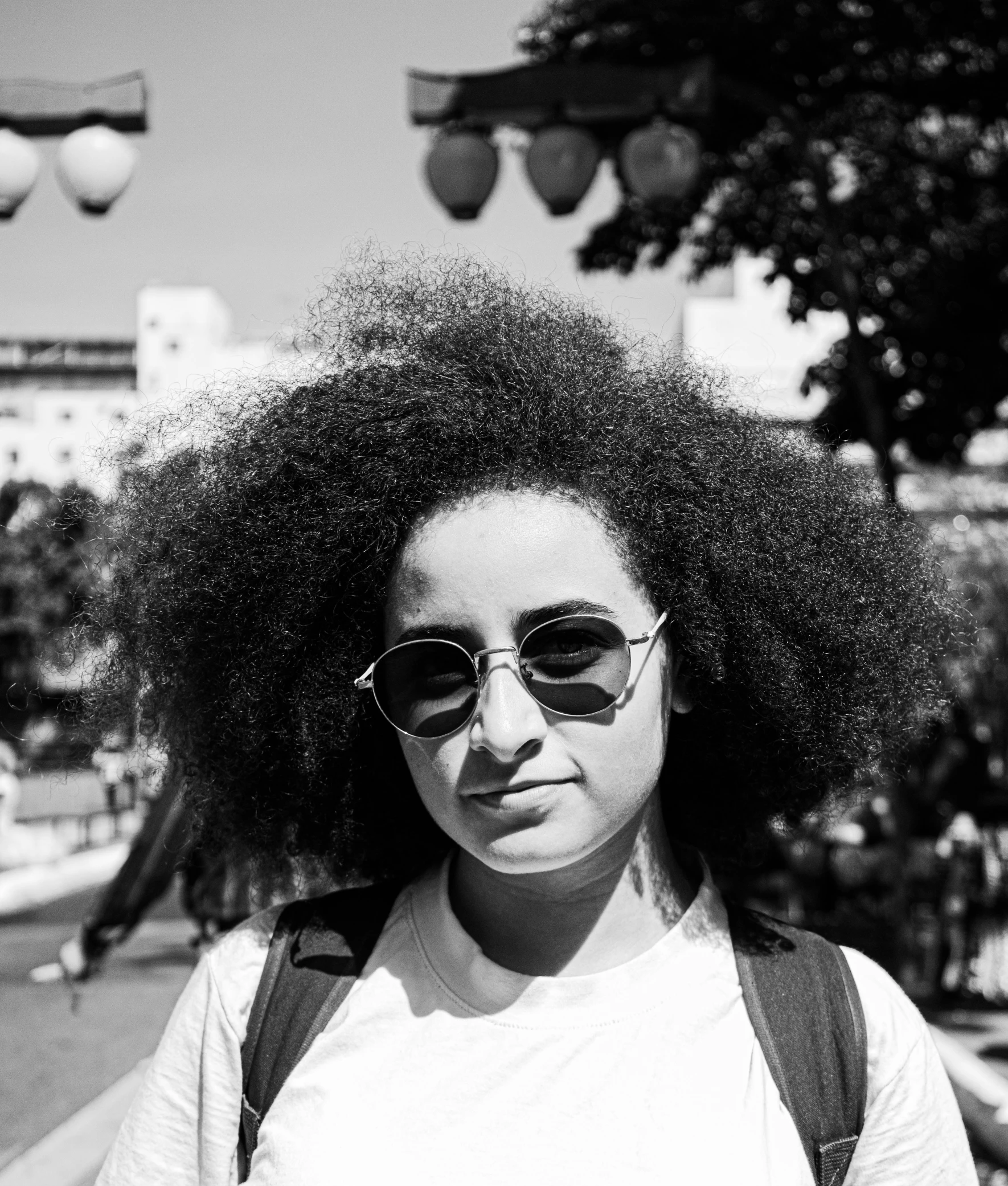 the girl has large afro hair standing on a street