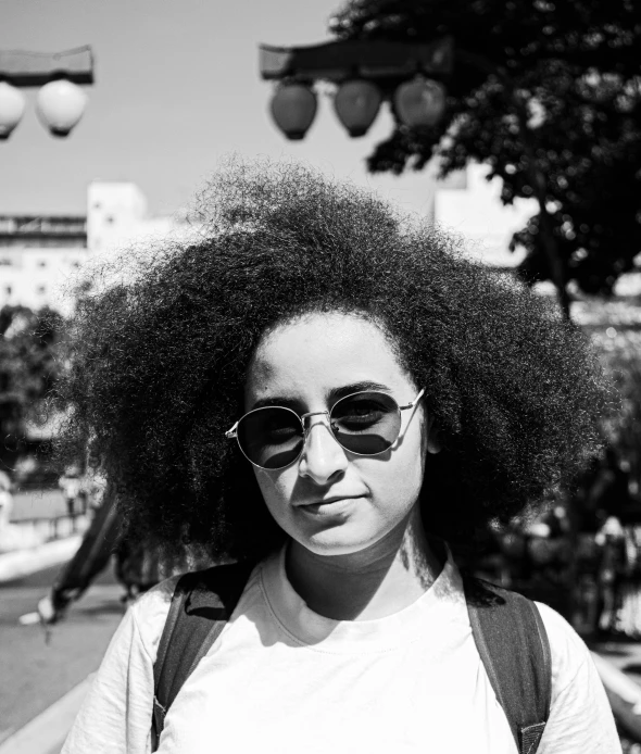 the girl has large afro hair standing on a street