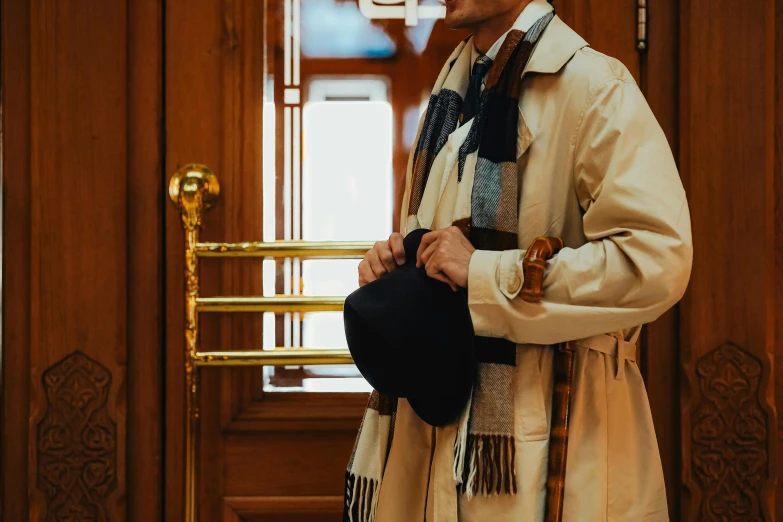 a man wearing a coat and scarf holding a hat