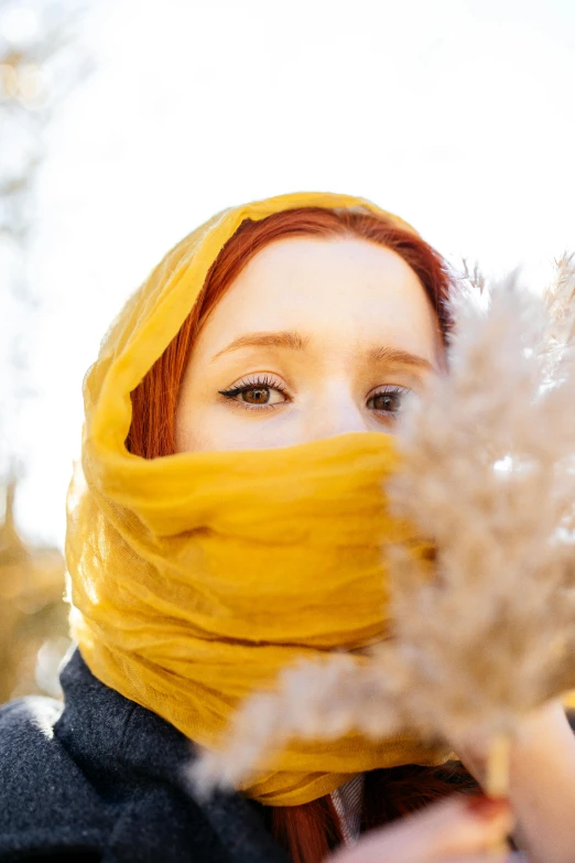 a woman with orange hair in a yellow scarf