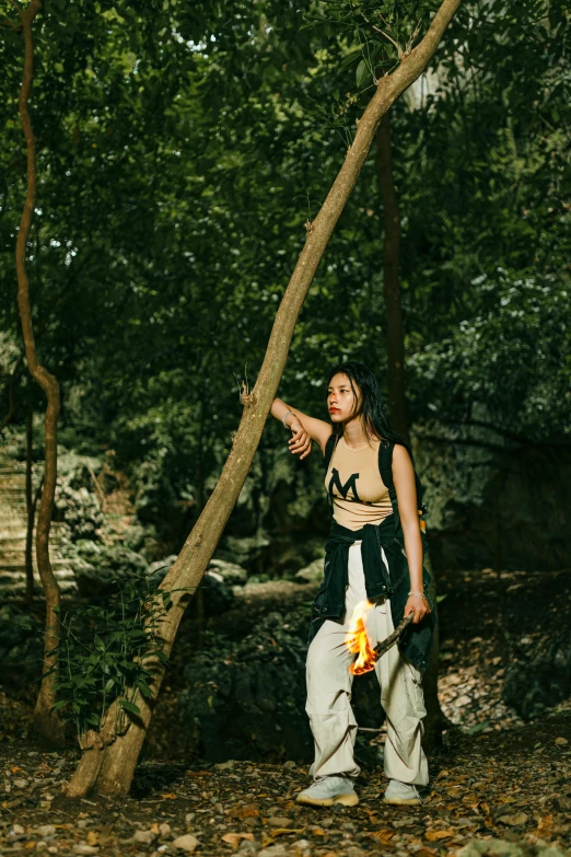 a woman is standing under the trees with her hand in her pocket