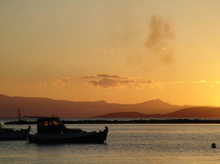 a boat on the water during sunset with a mountain in the background