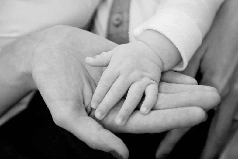 a close up s of the hands of two people holding a baby