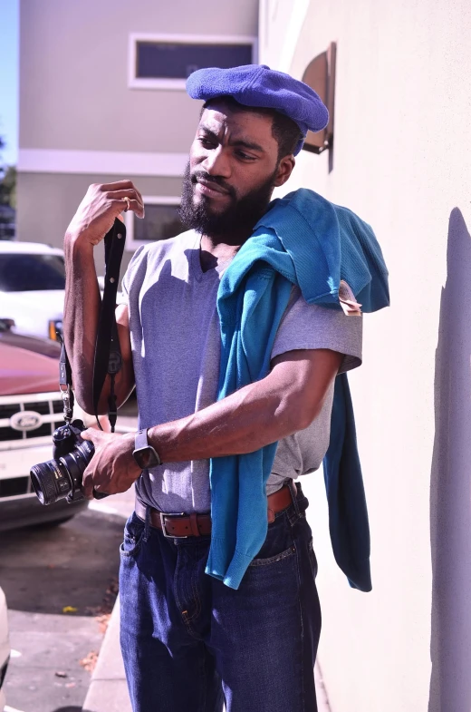 a man standing outside holding on to his hat and bag