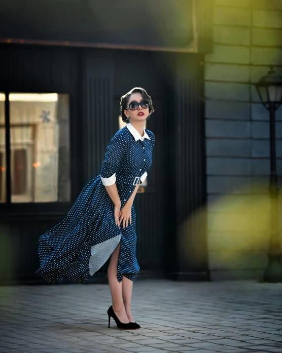 a woman wearing a dress with collar neck and sleeves is standing in the sun