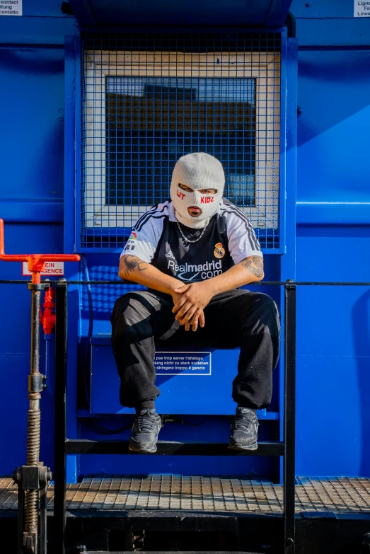 a person wearing a white mask sitting on a blue bench