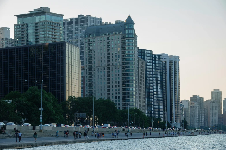 people are walking along the beach near some large buildings