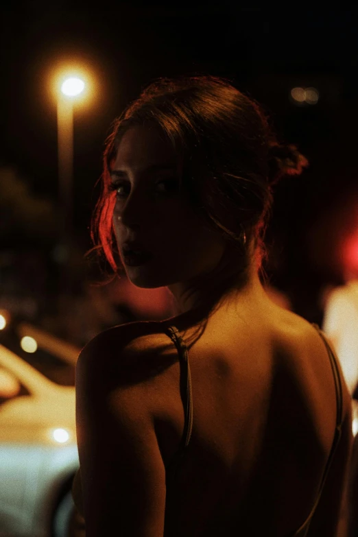 woman standing in the dark in front of parked cars