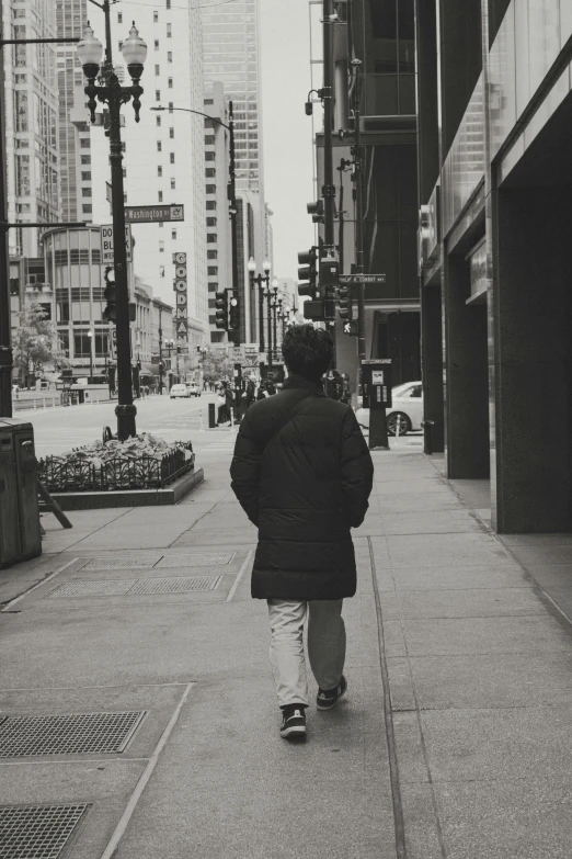 person walking down sidewalk by large buildings