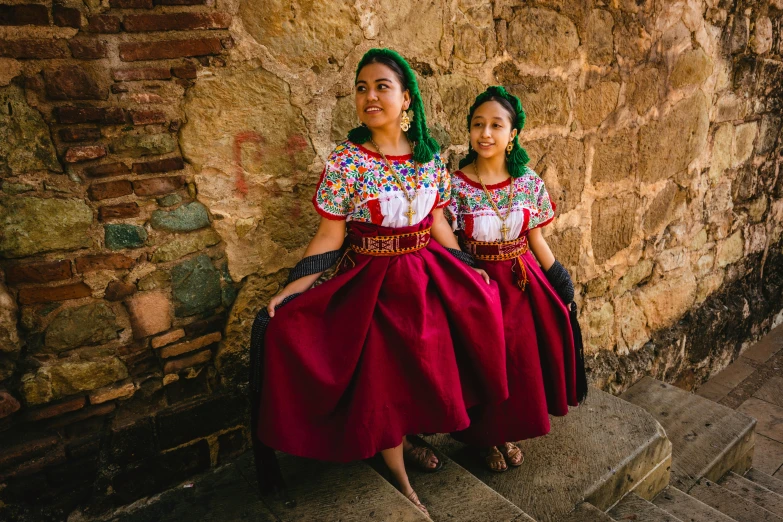 two girls are sitting on some steps with long hair