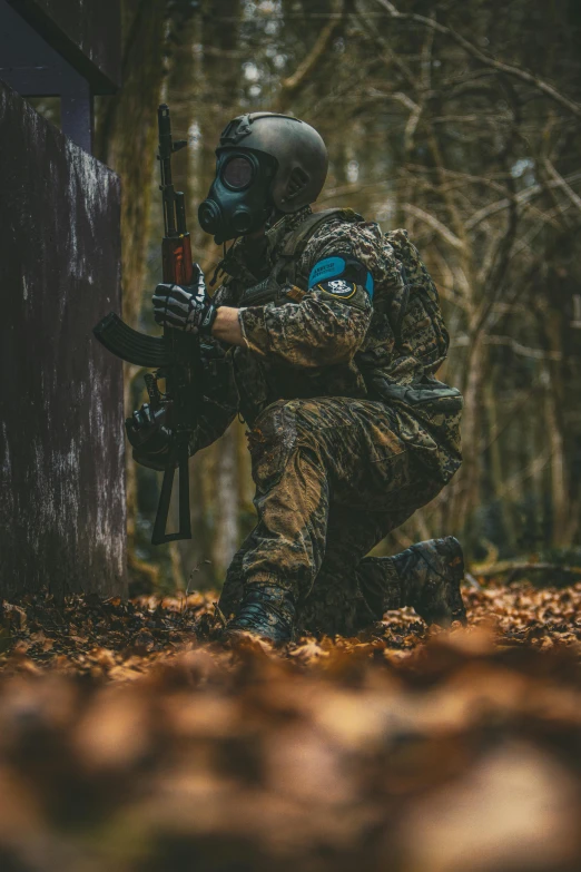 a man wearing a camouflage suit crouching in the woods while holding a rifle