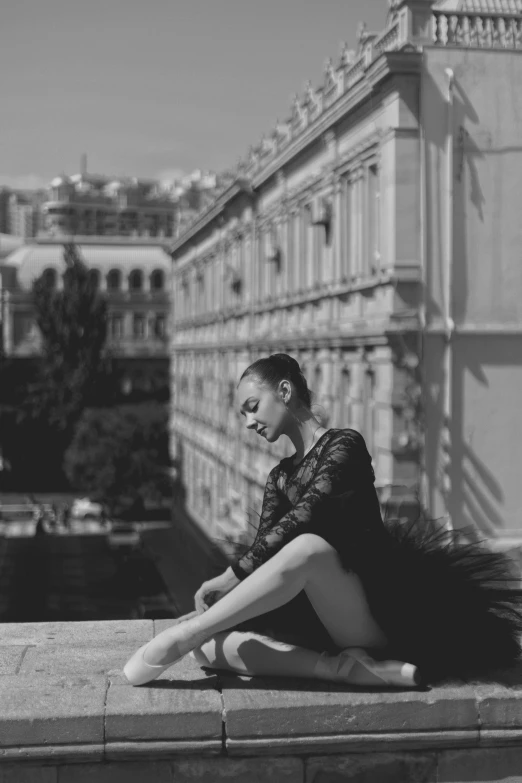 a woman sits on a ledge and looks at her cell phone